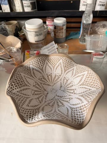 Unfired bowl with a crocheted doily pressed into the clay