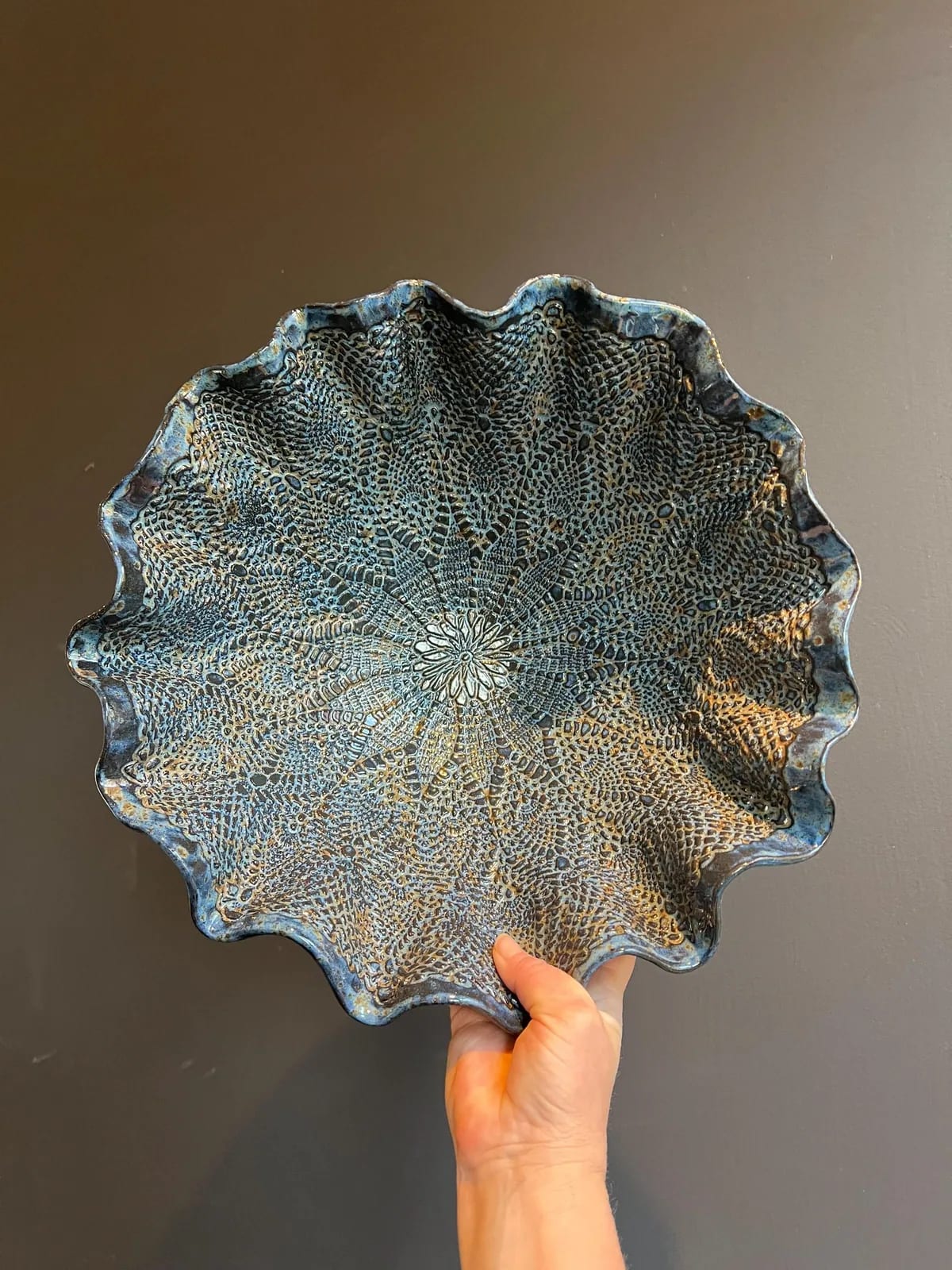 Handmade lace bowl by Jolanda, held up against a light wall